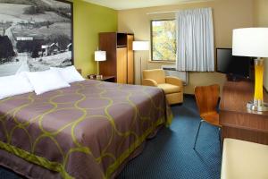 圣克莱尔斯维尔俄亥俄州圣克莱尔维尔威灵WV区速8酒店的酒店客房带一张大床和一把椅子