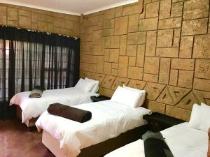 波罗瓜尼Klein Paradys Lodge - Polokwane的一间设有三张床和石墙的房间