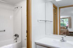 皮茨顿Knights Inn Pittston的浴室配有盥洗盆、镜子和浴缸