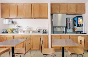 佩吉Travelodge by Wyndham Page, View of Lake Powell的厨房配有木制橱柜、2张桌子和冰箱。