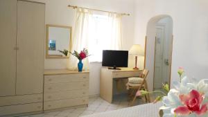 利帕里奥古斯都别墅酒店的一间卧室配有带电视和书桌的梳妆台。