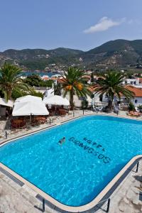 斯科派洛斯迪奥尼索斯酒店的一座棕榈树和遮阳伞的大型游泳池