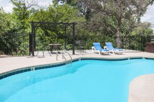 斯蒂尔沃特Microtel Inn by Wyndham Stillwater的一个带2把蓝色椅子和桌子的游泳池