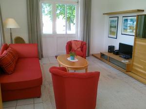 诺伊霍夫Villa Caprivi - Ferienwohnung 6的客厅配有红色椅子、桌子和电视