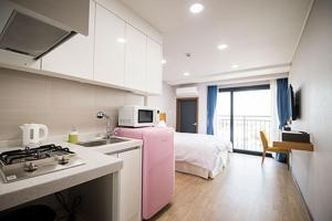 西归浦市W海洋旅馆的厨房配有床边的粉红色冰箱