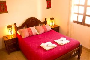 伊鲁亚Hostal Tacacho的一间卧室配有红色的床和2条毛巾