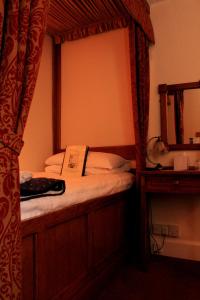 韦尔斯萨默塞特郡韦尔斯皇冠酒店的一间卧室配有一张带镜子的天蓬床