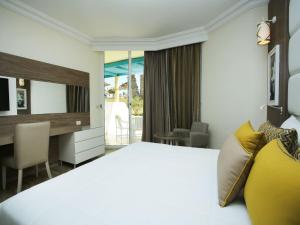 甘达坞伊港Sentido Bellevue Park的酒店客房带一张床、一张书桌和一面镜子