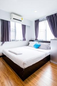 曼谷The Cube Sathorn Boutique Hotel เดอะ คิวบ์ สาทร บูติค โฮเทล Near BTS Surasak的一间卧室配有一张带白色床单和蓝色枕头的大床。