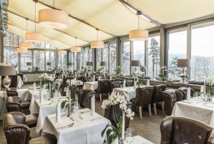 艾森纳赫埃森纳特贝格酒店的餐厅设有白色的桌椅和窗户。