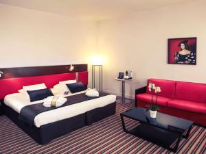 昂古莱姆法国昂古莱姆美居酒店的酒店客房,配有一张床和一张红色的沙发