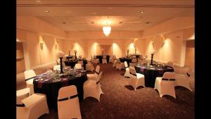 林赛Ramada by Wyndham Lindsay的宴会厅配有桌子、白色椅子和桌子。