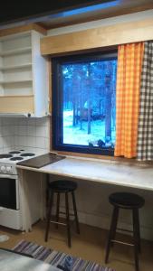 KakslauttanenKiiloselän Poropirtti的厨房配有带2张凳子的柜台和窗户。