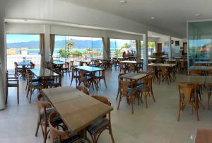 皮涅拉Hotel Pousada Santos的一间空餐厅,配有桌椅和窗户