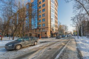 圣彼得堡Apartments at Yaroslavskiy prospekt的停在大楼前的一条雪覆盖的街道上的汽车