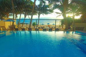 尼甘布Beacon Beach Hotel Negombo的一个带椅子和棕榈树的游泳池以及大海