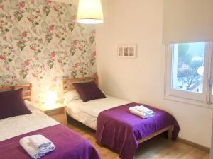 滨海托萨Apartamento Tossa de Mar的一间卧室设有两张带紫色床单的床和窗户。
