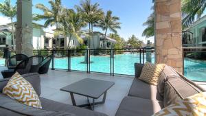 道格拉斯港Luxury Apartments at Temple Resort and Spa Port Douglas的一个带沙发和桌子的庭院,毗邻一个游泳池
