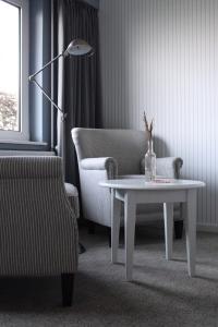 HvidbjergTambohus Kro & Badehotel的客厅配有桌子、椅子和灯