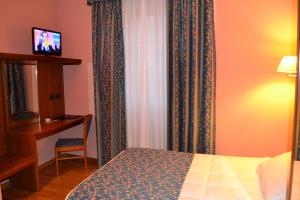 瓦拉洛意大利达尔贝戈酒店的一间卧室配有一张床、一张书桌和窗帘