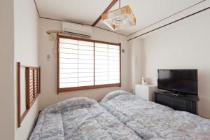 东京新大久保石亭酒店的一间卧室配有一张床和一台平面电视