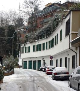 博洛尼亚charming new loft的一条雪覆盖的街道,在建筑物前停放汽车