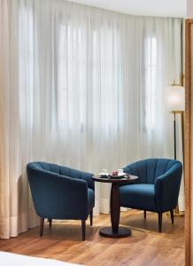 巴塞罗那H10麦迪逊四星素普酒店的客厅配有2把蓝色椅子和桌子