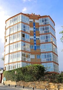 贝纳尔马德纳朵拉玛公寓酒店的一座高大的砖砌建筑,上面有蓝色的标志