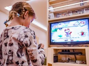 卡斯特尔罗托Luxury and Nature House Moarlhof的一名年轻女孩在电视上玩电子游戏