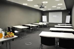 布拉格布拉格大都会酒店的一间教室,配有白色的桌椅和屏幕