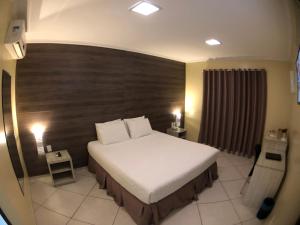 FlorianoGaroto Park Hotel的一间卧室配有一张大床和木制床头板