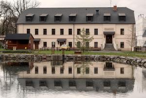 奥帕瓦Panský mlýn的一座白色的大建筑,在水体中反射