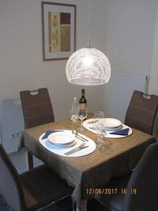 巴特德里堡Haus Harmonie的一张桌子,上面放有盘子,一瓶葡萄酒和一盏灯