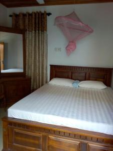 尼甘布Nethmi Rooms的卧室配有一张床铺,墙上挂着粉红色的遮阳伞
