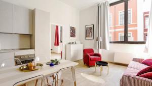 米兰贝尔贡佐利广场意式公寓的客厅配有桌子和红色椅子