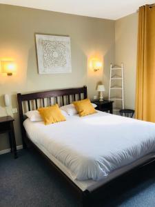 Gamarde-les-Bainsl'auberge的卧室配有一张带黄色枕头的大型白色床。