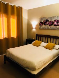 Gamarde-les-Bainsl'auberge的一间卧室配有一张带黄色枕头的床和一扇窗户