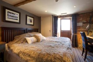 Brown CandoverThe Woolpack Inn的一间卧室配有一张床、一张书桌和一个窗户。