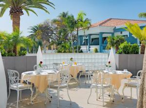 阿德耶阿德里安科隆瓜纳哈尼成人酒店的一个带桌椅的庭院,棕榈树
