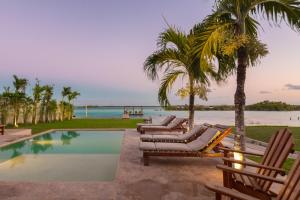巴卡拉尔Hotel CasaBakal - A pie de Laguna - Bacalar的一个带躺椅和棕榈树的游泳池以及大海