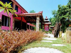 乌巴图巴Bali Suites Itamambuca的一座粉红色建筑和一座花园