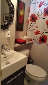 Sainte-Julie安妮德劳因艺术加膳食酒店的浴室设有水槽和带花卉淋浴帘的卫生间。