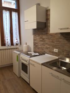 威尼斯Ca' del Megio的厨房配有白色橱柜、水槽和炉灶。