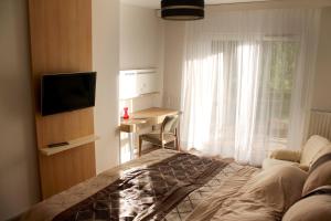 韦伦采Velence Resort Apartman的一间卧室配有一张床、一张书桌和一个窗户。