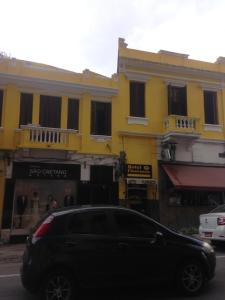 圣保罗Hotel Florêncio的停在黄色建筑前面的黑色汽车