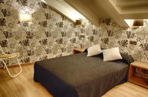 莱昂勒佩提特莱昂酒店的一间卧室配有一张黑色和白色壁纸的床