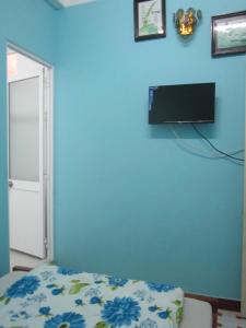 大叻Bình An的卧室设有蓝色墙壁,墙上配有电视
