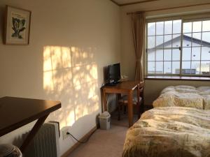日光日光小森林旅馆的一间卧室设有两张床、一张桌子和一个窗口。