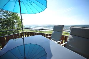 吕德斯海姆das Rebenhaus的阳台上配有带遮阳伞和椅子的桌子