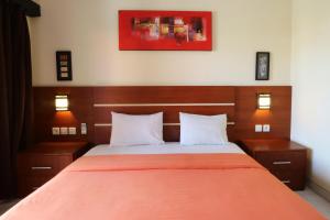 库塔Kondra Premiere Guest House Kuta的一间卧室配有一张带橙色毯子的床